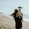Frau trägt ihren Hund am Strand