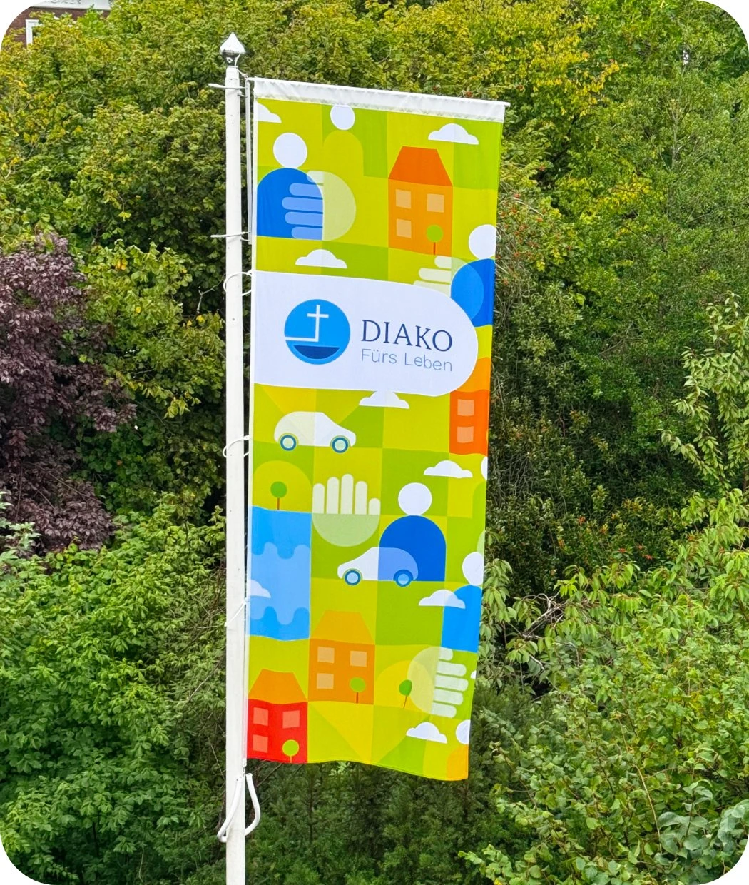 h2_diako_teaser_07.jpg Eine bunte Diako Fahne mit dem neuen Design draußen an einem Fahnenmast