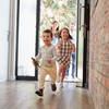 Zwei kleine Kinder rennen fröhlich durch die Tür ins Haus