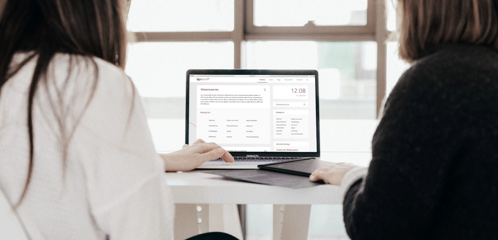 Zwei Frauen am Tisch blicken auf ein Notebook mit dem Intranet von ttp
