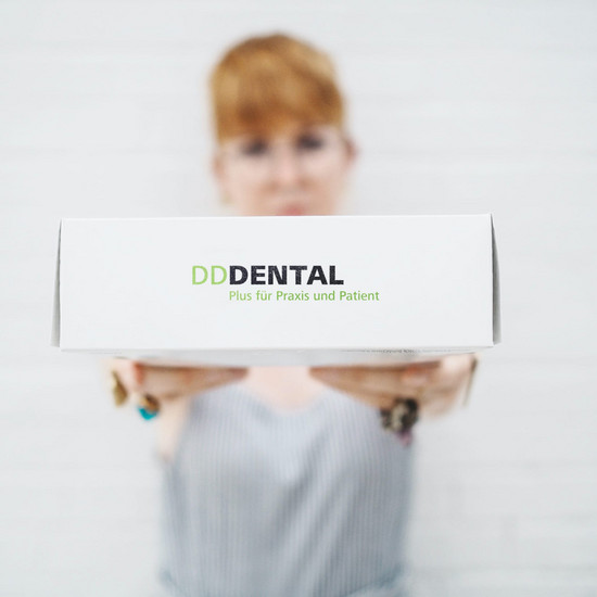 Frau hält weißes Paket mit Logo DD Dental