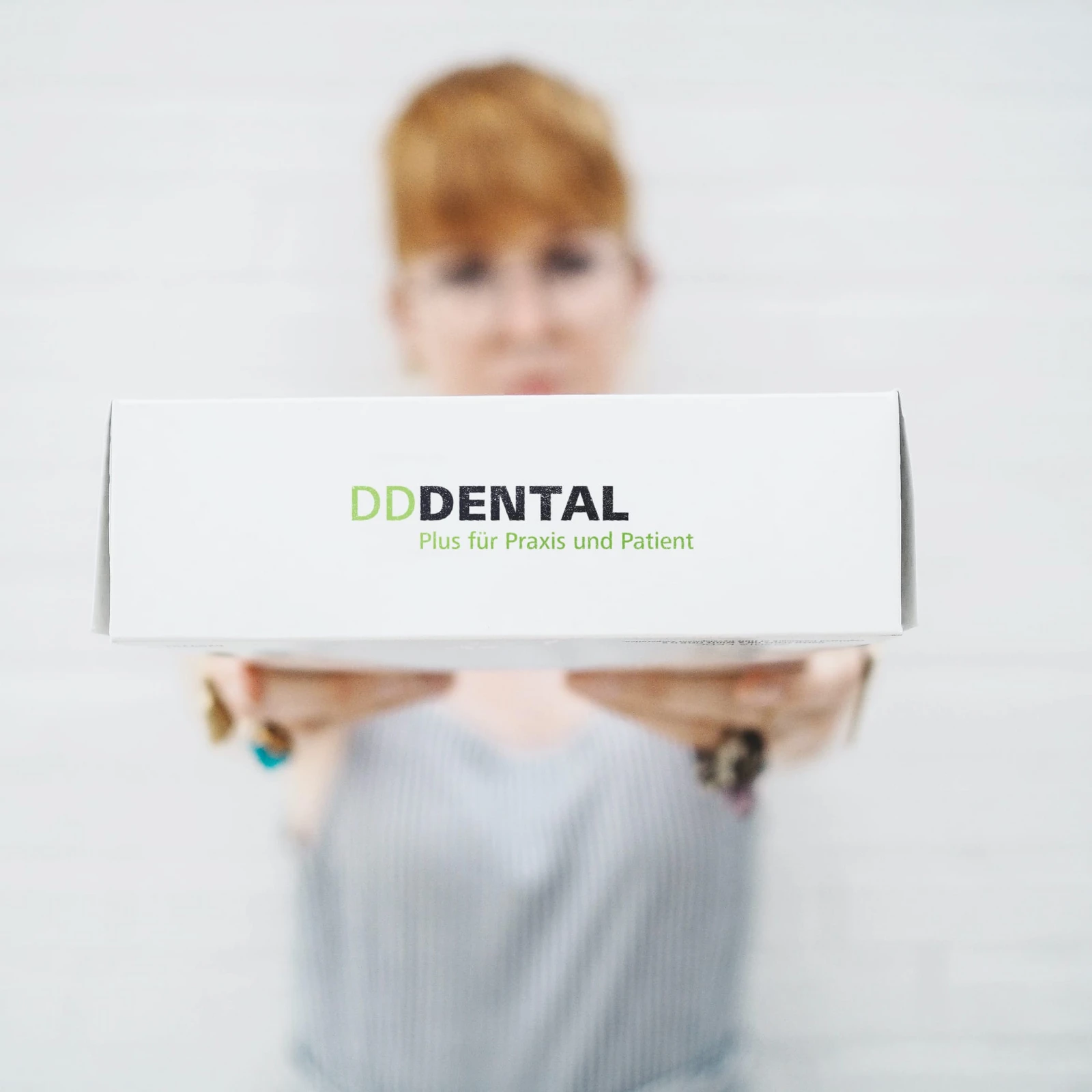hochzwei_ddd_teaser_01_hauptteaser.jpg Frau hält weißes Paket mit Logo DD Dental