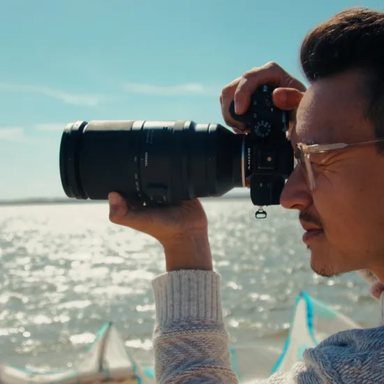 Foto eines jungen Mannes am Strand wie er mit einer Spiegelreflexkamera den Horizont fotografiert