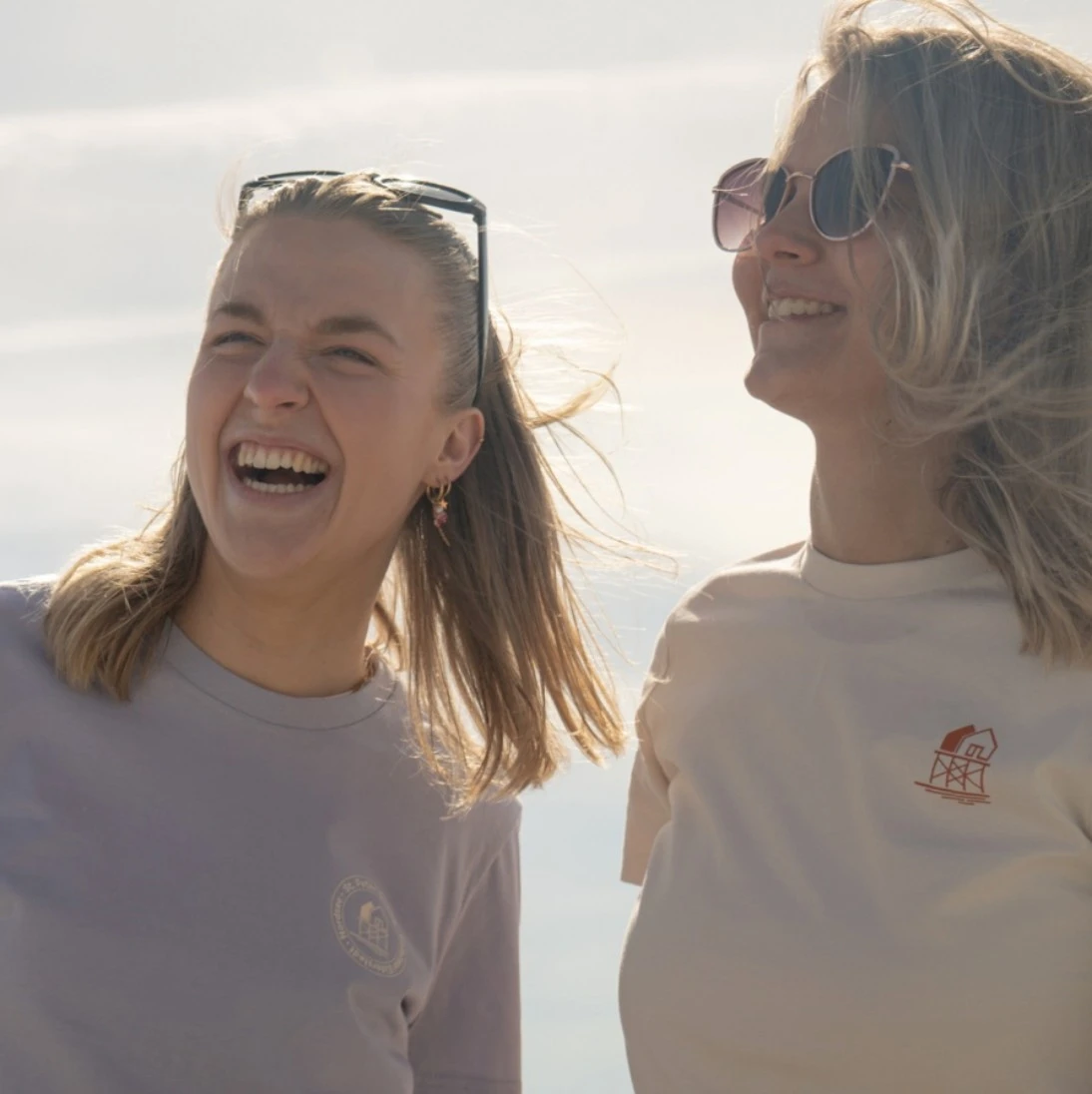 Zwei Frauen stehen in der Sonne und lachen