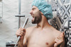 Ein Mann mit blauer Badekappe singt unter der Dusche