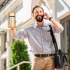 Ein Mann steht mit seinem Handy auf der Straße und hält eine Thermoskanne in der Hand