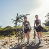 Zwei Rennradfahrerinnen gehen am Strand