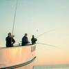 Drei Angler angeln von einem Schiff
