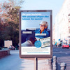 Anzeigenstele an Straße zeigt Seniorin und Tablet sowie Text 