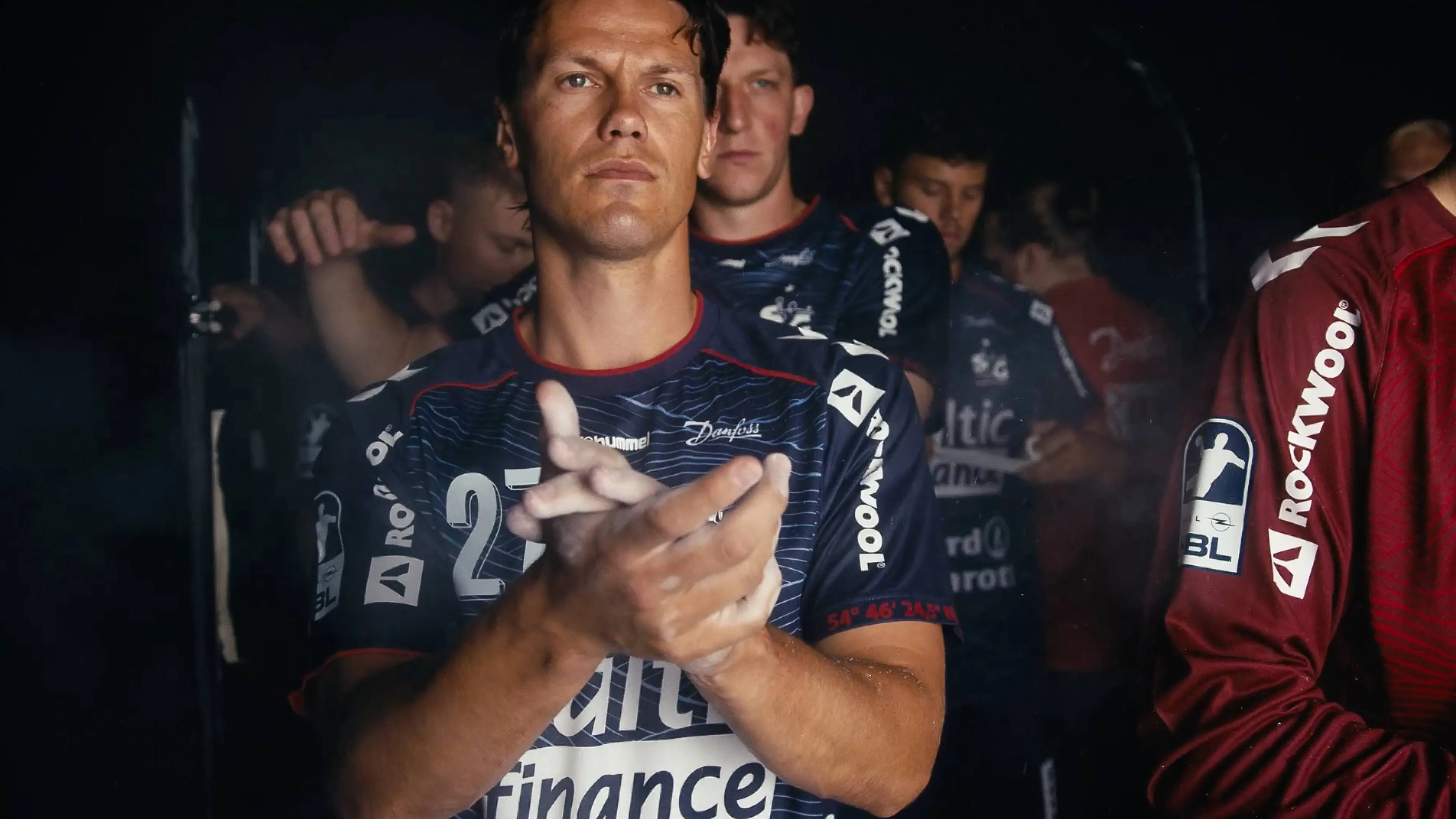 h2_sg_einlauftrailer_slider_03.jpg Foto der SG Spieler im Halbdunklen. Ganz vorne Aksel Horgen, hinter ihm Lasse Møller