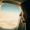 Frau blickt aus Flugzeugfenster auf Wölkchen