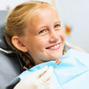 Lächelndes blondes Mädchen im Zahnarztstuhl