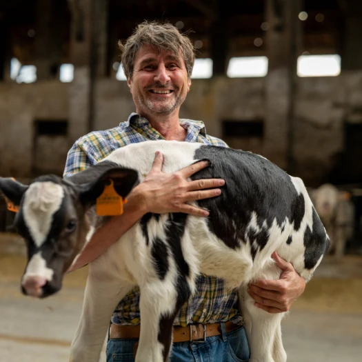 Ein Bauer hält sein Kalb im Arm