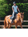 Eine Reiterin sitzt auf ihrem braunen Pferd.